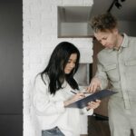 Woman signing a clipboard while technician explains service details