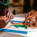 Hands analyzing colorful charts and graphs during a branding and market strategy discussion focused on competitor positioning.