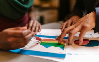 Hands analyzing colorful charts and graphs during a branding and market strategy discussion focused on competitor positioning.
